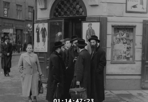 Men talking outside a clothing shop, Kraków, 1936
