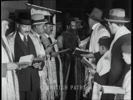 British Pathé frame: men and boys in tallisos and hats; one holds a Torah scroll with a Magen David on the mantle