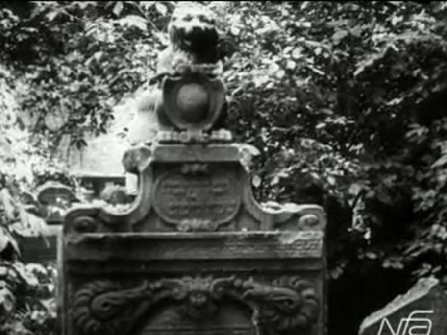 1926 film frame: Hendl Bassevi’s grave, a seated lion with its paws on a shield