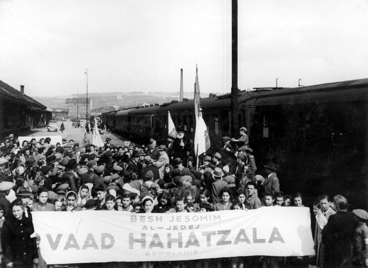 Yad Vashem FA160/37: Vaad Hahatzala banner and crowd at the Prague train station ceremony