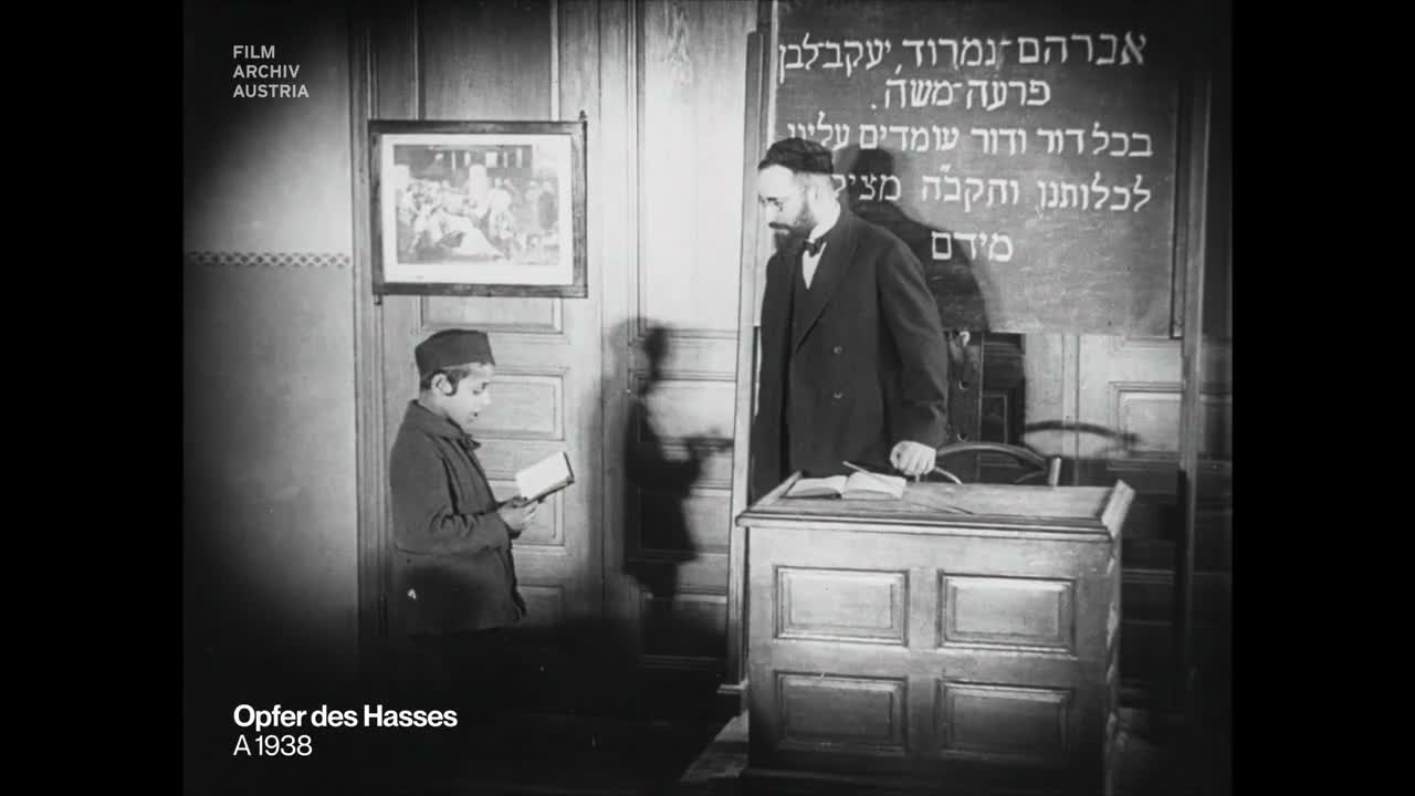 A boy and teacher beside a blackboard with Hebrew names and a passage from the Haggadah, Vienna, 1923