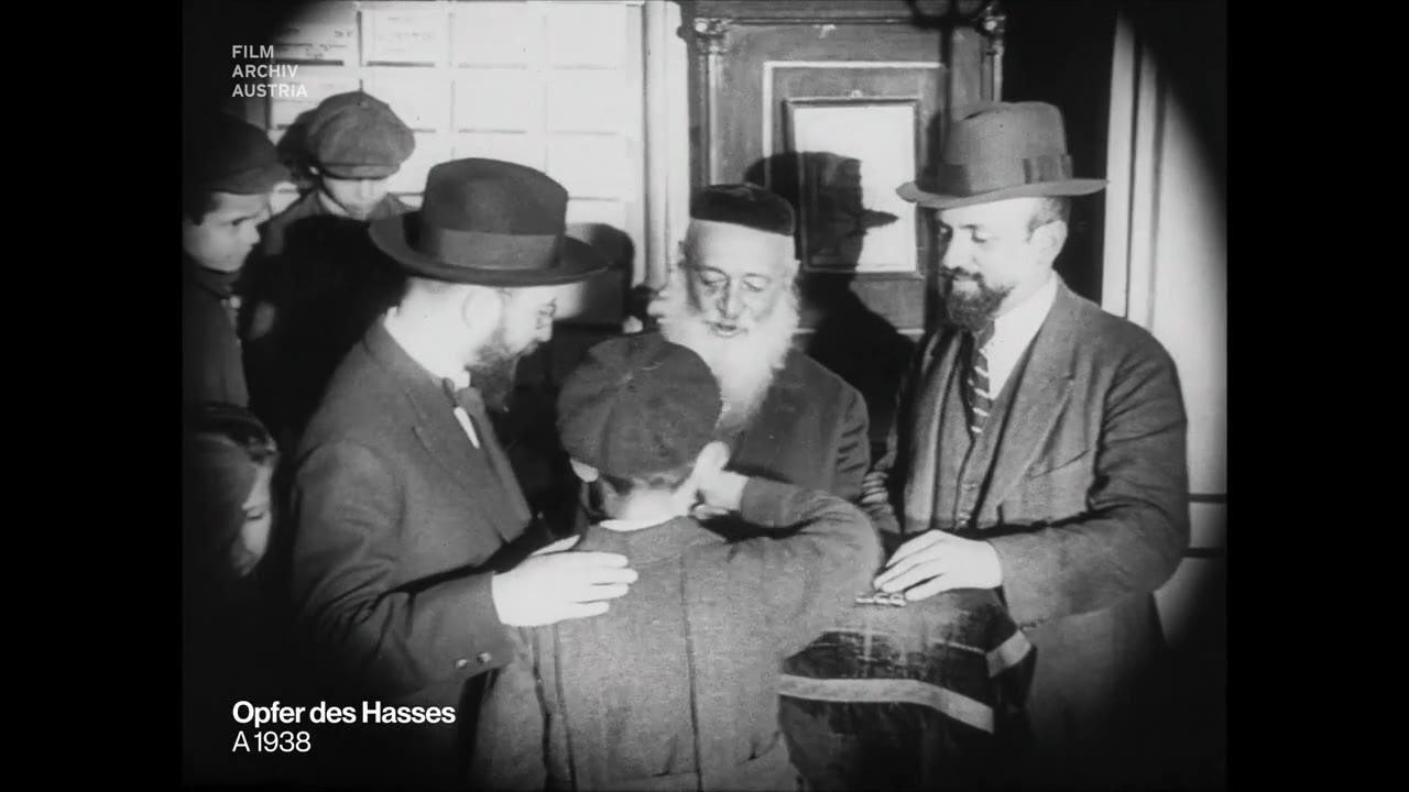 A boy at the table with Rabbi Yeshaya Furst, kissing the rav’s hand as he receives a candy, Vienna, 1923