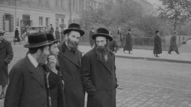 Four men in coats and hats standing on a street in Kazimierz, Kraków, 1936